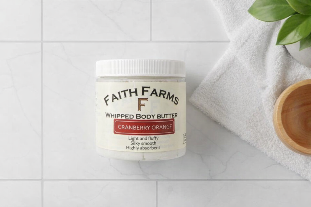 Jar of Faith Farms cranberry orange whipped body butter on a white surface with a towel and plant in the background.